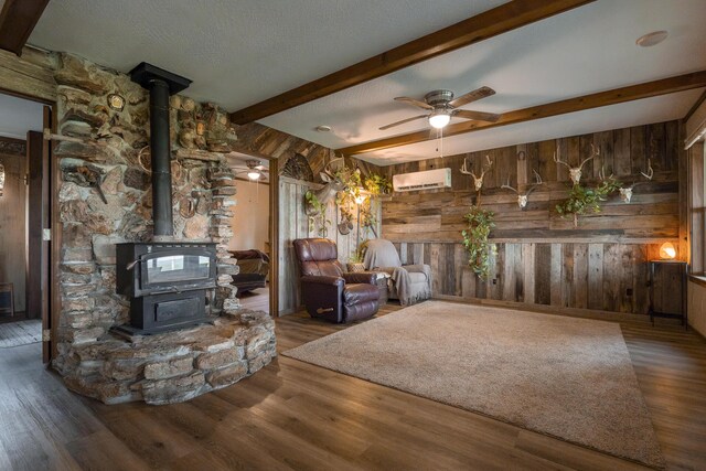 651/TBD Round Robin Ln, Yellville, AR 72687 - living room featuring an AC wall unit, wooden walls, a wood stove, ceiling fan, and wood finished floors