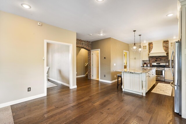 807 S Stanford Dr, Rogersville, MO 65742 - kitchen with custom exhaust hood, appliances with stainless steel finishes, dark wood finished floors, light stone countertops, and a kitchen bar