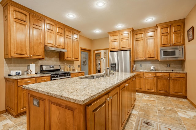 8326 Shinnecock Dr, Nixa, MO 65714 - kitchen featuring appliances with stainless steel finishes, under cabinet range hood, a sink, brown cabinetry, and light stone countertops