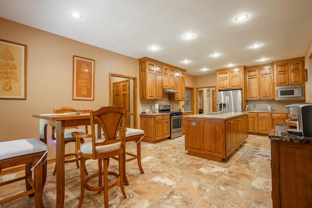 8326 Shinnecock Dr, Nixa, MO 65714 - kitchen featuring stainless steel appliances, a sink, backsplash, under cabinet range hood, and recessed lighting