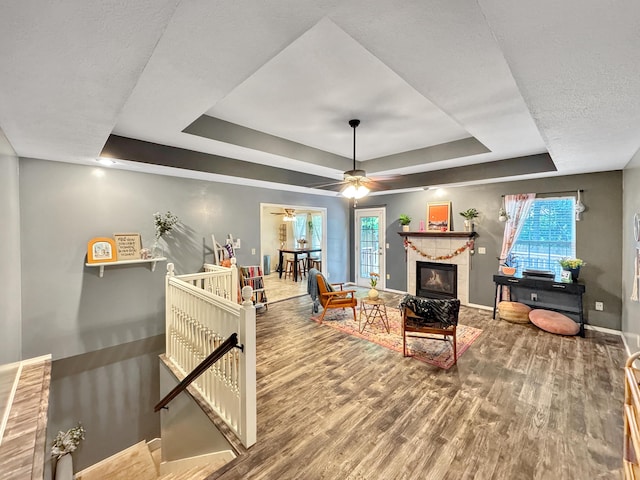 5726 S Fairview Ave, Springfield, MO 65810 - living area with a tray ceiling, baseboards, wood finished floors, ceiling fan, and a fireplace