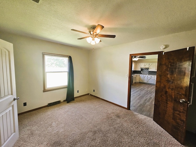 107 W Poplar St, El Dorado Springs, MO 64744 - empty room with dark colored carpet, ceiling fan, baseboards, and a textured ceiling