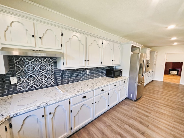 107 W Poplar St, El Dorado Springs, MO 64744 - kitchen with stainless steel appliances, under cabinet range hood, light wood-style flooring, white cabinets, and backsplash