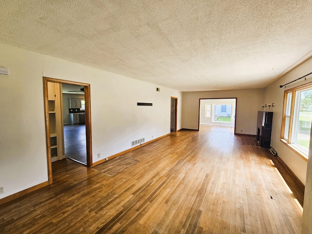 107 W Poplar St, El Dorado Springs, MO 64744 - unfurnished living room with hardwood / wood-style flooring, a textured ceiling, and baseboards