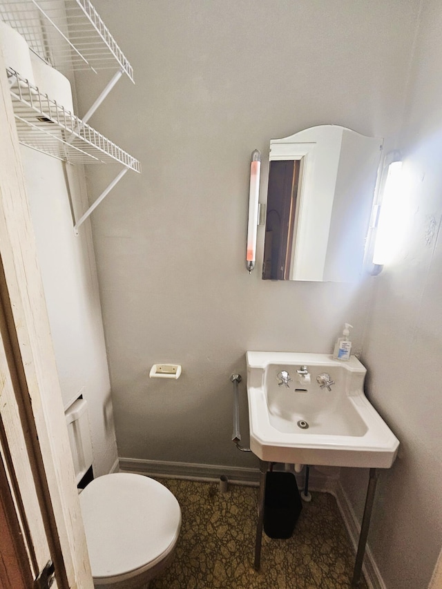 107 W Poplar St, El Dorado Springs, MO 64744 - bathroom featuring baseboards, toilet, and a sink