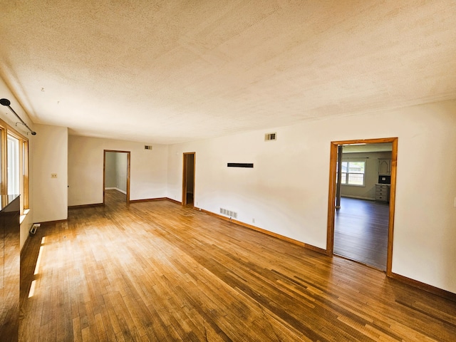 107 W Poplar St, El Dorado Springs, MO 64744 - spare room featuring a textured ceiling, hardwood / wood-style floors, and baseboards