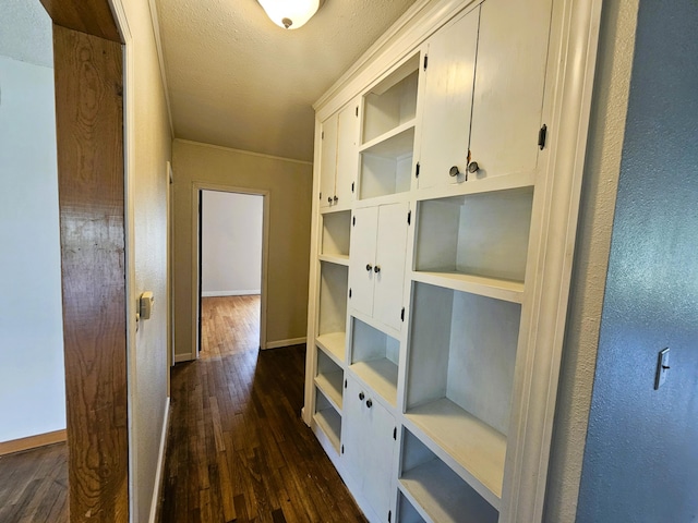 107 W Poplar St, El Dorado Springs, MO 64744 - hallway with dark wood-type flooring, baseboards, a textured ceiling, and a textured wall