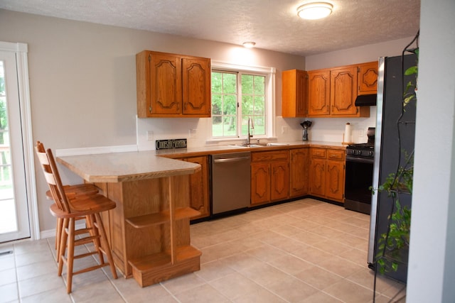18627 Farm Rd Unit 1075, Exeter, MO 65647 - kitchen featuring appliances with stainless steel finishes, a peninsula, a sink, under cabinet range hood, and brown cabinets