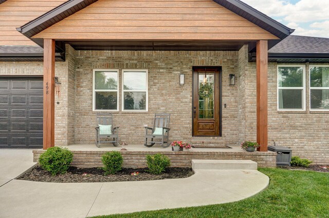 498 Mockingbird, Rogersville, MO 65742 - property entrance featuring a porch, an attached garage, brick siding, a shingled roof, and concrete driveway