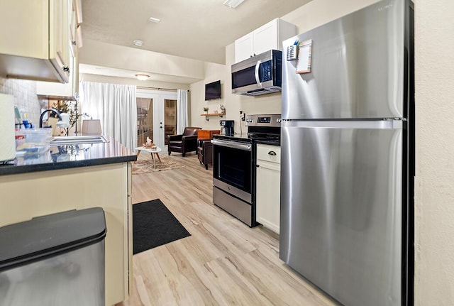 180 Grace Chapel Rd Unit 321, Blue Eye, MO 65611 - kitchen with appliances with stainless steel finishes, light wood finished floors, dark countertops, white cabinets, and french doors
