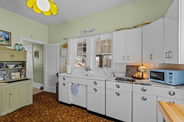 310 S Main St, Licking, MO 65542 - kitchen with white microwave, light countertops, white cabinets, a sink, and tasteful backsplash