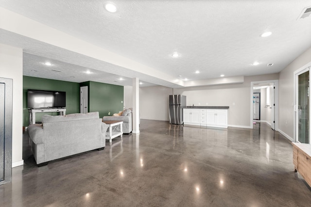 living room with finished concrete floors, recessed lighting, baseboards, and a textured ceiling
