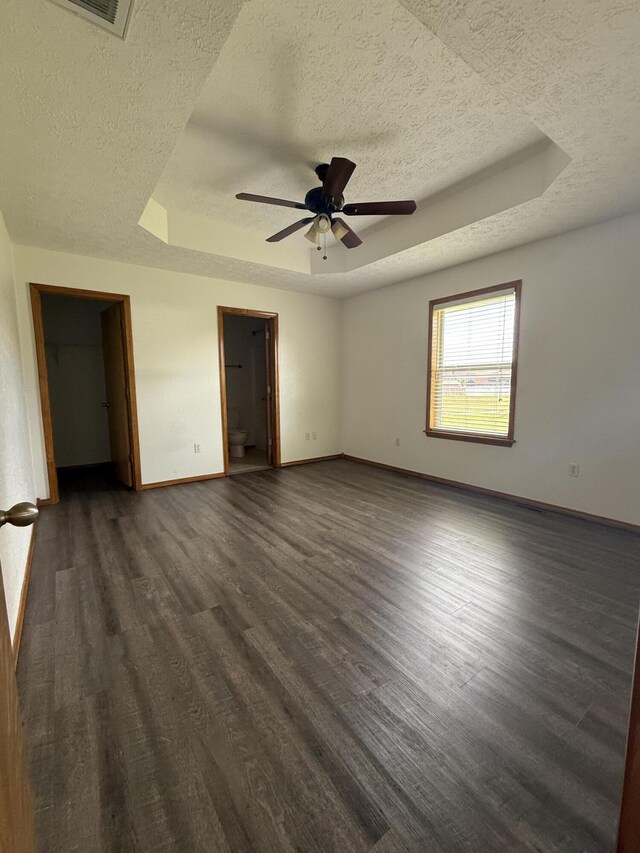 6004 N 6th Ave, Ozark, MO 65721 - unfurnished bedroom with a tray ceiling, a textured ceiling, baseboards, and dark wood-style flooring