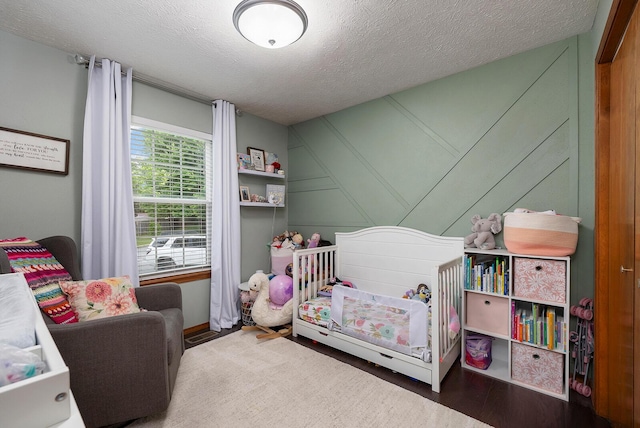 5204 W Turnberry Ct, Ozark, MO 65721 - bedroom featuring a textured ceiling, a decorative wall, wood finished floors, and a nursery area