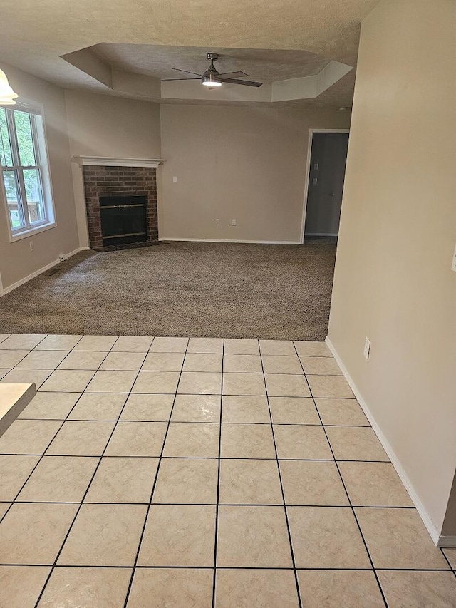 3807 S Leawood Ave, Springfield, MO 65807 - unfurnished living room featuring a raised ceiling, a ceiling fan, light carpet, a textured ceiling, and a brick fireplace