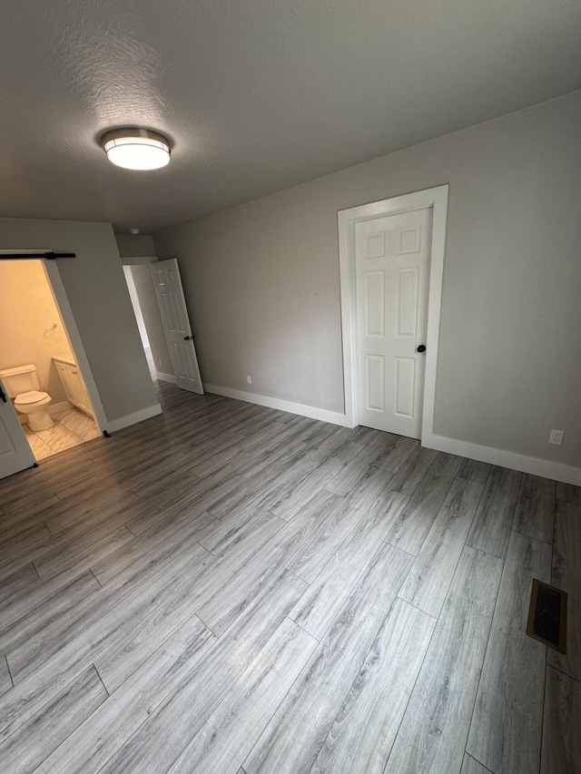 108 Jasper St, Aurora, MO 65605 - unfurnished bedroom featuring wood finished floors, baseboards, connected bathroom, and a textured ceiling