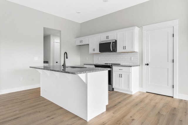 1312 N Maxine Ave, Nixa, MO 65714 - kitchen with stainless steel appliances, a sink, dark stone counters, white cabinets, and backsplash