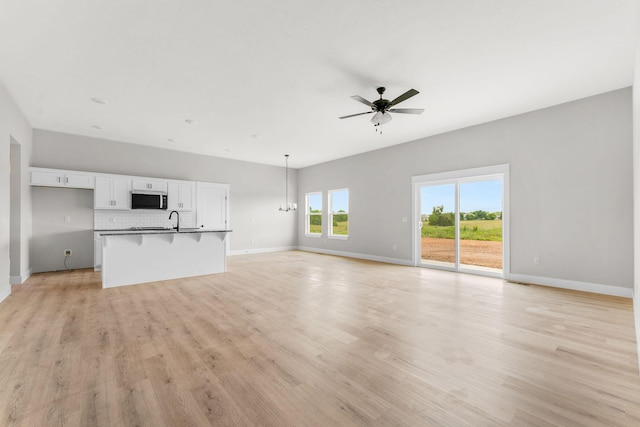 1312 N Maxine Ave, Nixa, MO 65714 - unfurnished living room featuring a ceiling fan, a sink, baseboards, and light wood-style floors