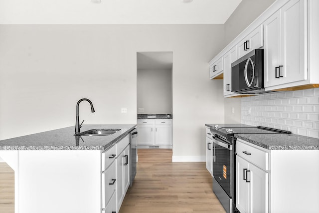 1312 N Maxine Ave, Nixa, MO 65714 - kitchen featuring stainless steel appliances, a sink, light wood-style flooring, dark stone counters, and white cabinets