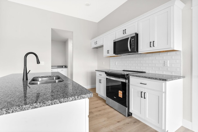 1312 N Maxine Ave, Nixa, MO 65714 - kitchen featuring appliances with stainless steel finishes, a sink, dark stone counters, white cabinets, and light wood-style flooring