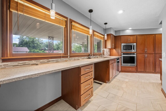 1622 Oakland Ave, Bolivar, MO 65613 - kitchen featuring appliances with stainless steel finishes, brown cabinets, hanging light fixtures, light stone counters, and decorative backsplash