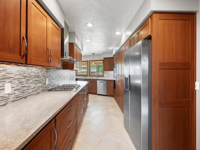1622 Oakland Ave, Bolivar, MO 65613 - kitchen with appliances with stainless steel finishes, brown cabinets, wall chimney range hood, a textured ceiling, and backsplash