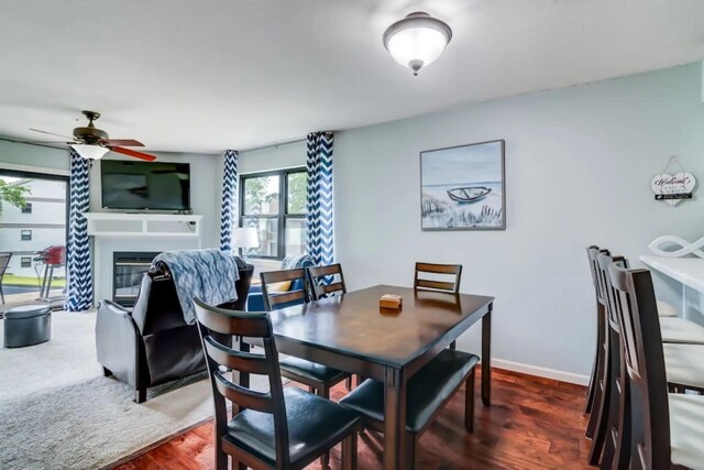 123 Bunker Ridge Dr Unit 4, Branson, MO 65616 - dining space featuring a glass covered fireplace, a ceiling fan, dark wood-type flooring, and baseboards