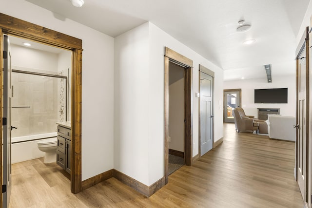 hallway with light wood-type flooring, baseboards, and recessed lighting