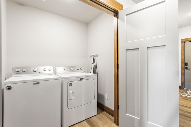 laundry room with washing machine and dryer, light wood-style flooring, and baseboards