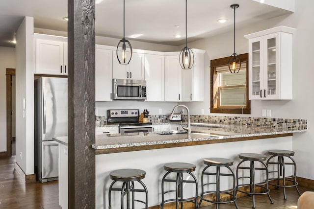 kitchen with stainless steel appliances, glass insert cabinets, dark wood-style flooring, a sink, and light stone countertops