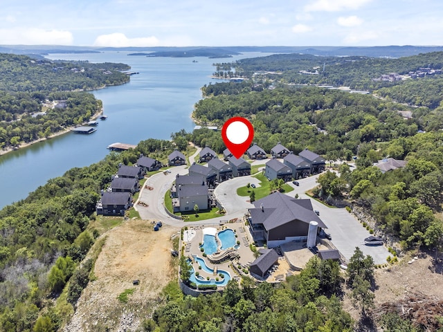 view of property location featuring a large body of water, a pool, a heavily wooded area, and nearby suburban area
