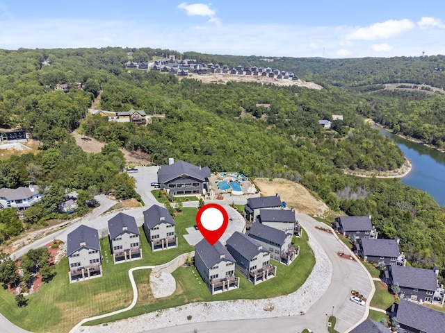 aerial view of property's location with a nearby body of water, nearby suburban area, and a forest