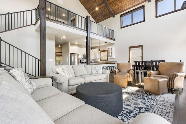 living area featuring high vaulted ceiling, hardwood / wood-style flooring, wooden ceiling with exposed beams, and stairs
