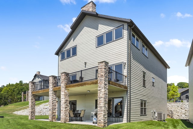 rear view of property with a yard, a chimney, a patio area, central AC unit, and a deck