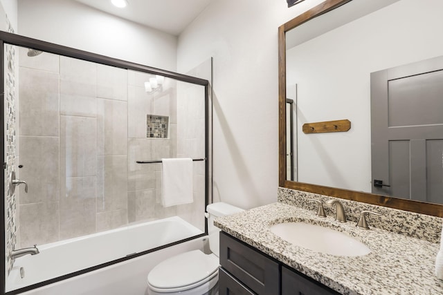 bathroom with vanity, toilet, and combined bath / shower with glass door