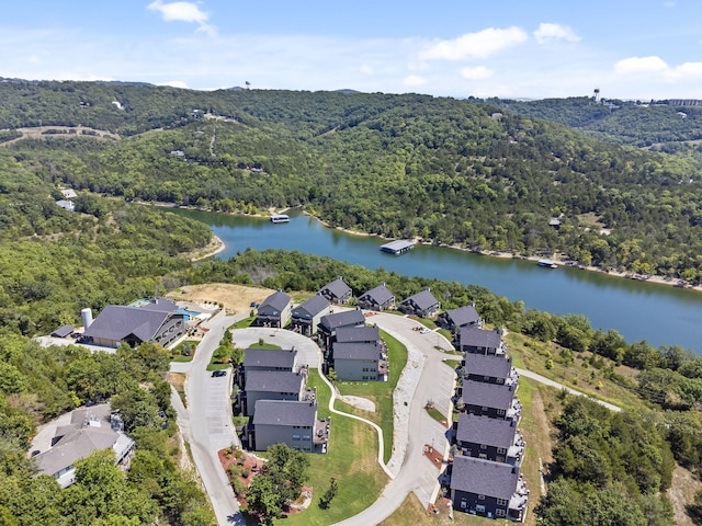view of property location with a forest, a large body of water, and nearby suburban area