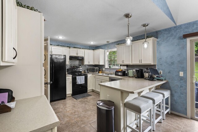 1206 S Solaira St, Ozark, MO 65721 - kitchen with black appliances, under cabinet range hood, a peninsula, a kitchen bar, and light countertops