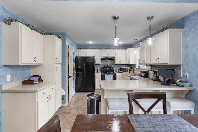 1206 S Solaira St, Ozark, MO 65721 - kitchen featuring black appliances, under cabinet range hood, a peninsula, light countertops, and a kitchen bar