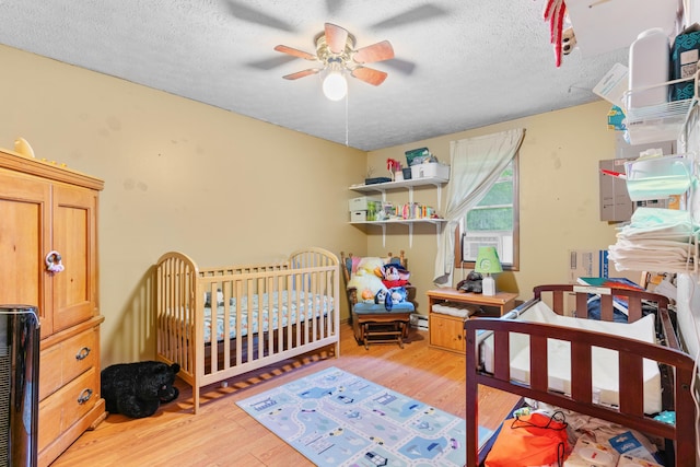 1408 Rockhill Cir, Ozark, MO 65721 - bedroom with light wood-style flooring, a textured ceiling, baseboard heating, cooling unit, and a crib