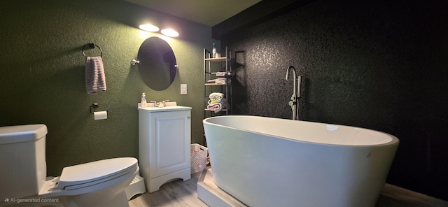 414 3rd St, Anderson, MO 64831 - bathroom with a textured wall, a freestanding bath, vanity, toilet, and wood finished floors