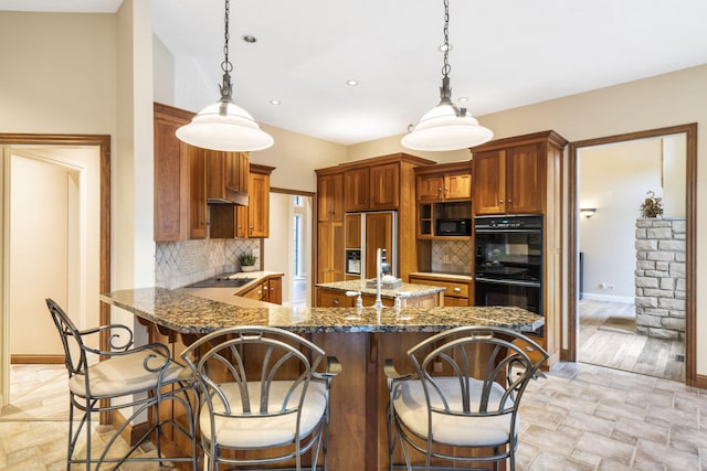 2421 Candlebark Ln, Lebanon, MO 65536 - kitchen featuring black appliances, decorative backsplash, dark stone counters, a kitchen bar, and pendant lighting
