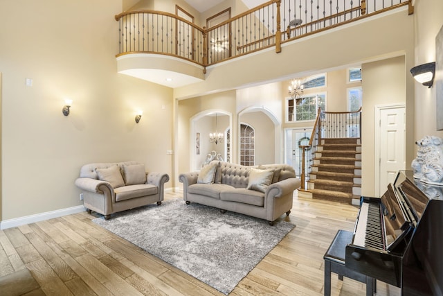 2421 Candlebark Ln, Lebanon, MO 65536 - living area featuring a chandelier, arched walkways, a towering ceiling, stairway, and wood finished floors
