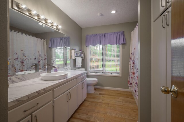 10703 Lawrence Unit 2230, Monett, MO 65708 - bathroom featuring vanity, toilet, wood finished floors, a textured ceiling, and baseboards