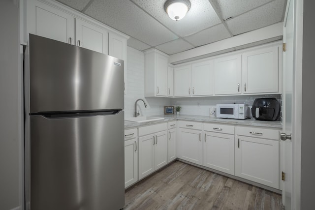 10703 Lawrence Unit 2230, Monett, MO 65708 - kitchen with freestanding refrigerator, a sink, a drop ceiling, white microwave, and white cabinets