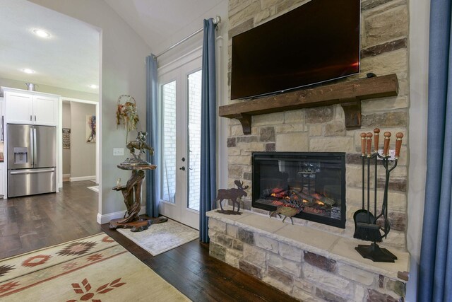 722 Seven Pines Dr, Saddlebrooke, MO 65630 - living area with dark wood-type flooring, vaulted ceiling, baseboards, and a stone fireplace