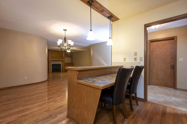 2117 E Wornall Pl, Springfield, MO 65804 - kitchen with a chandelier, wood finished floors, a peninsula, a kitchen breakfast bar, and hanging light fixtures