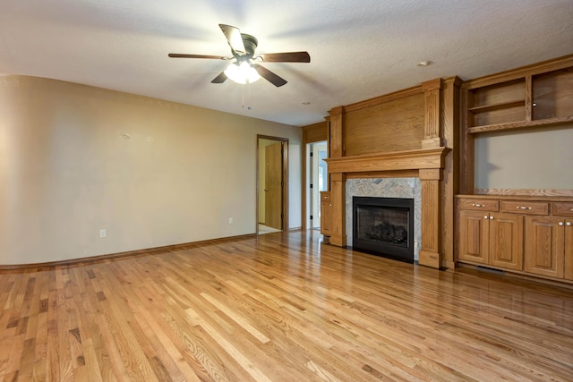 2117 E Wornall Pl, Springfield, MO 65804 - unfurnished living room with light wood-type flooring, a ceiling fan, and a high end fireplace