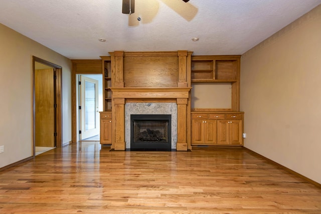 2117 E Wornall Pl, Springfield, MO 65804 - unfurnished living room featuring light wood finished floors, a ceiling fan, a premium fireplace, and a textured ceiling