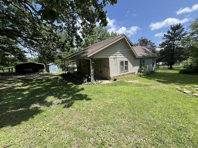 1010 Pine St, Cabool, MO 65689 - view of property exterior featuring a storage unit, a carport, a yard, and a shingled roof
