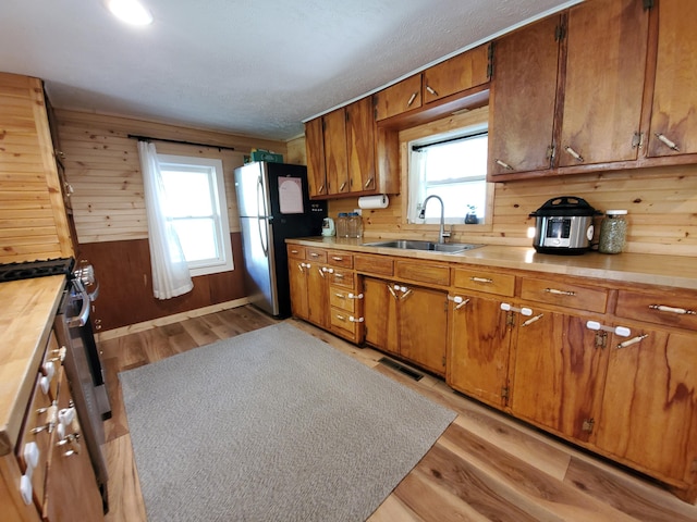 1010 Pine St, Cabool, MO 65689 - kitchen with stainless steel appliances, light wood finished floors, brown cabinetry, wood walls, and butcher block countertops